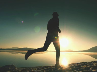 Uzun kumsalda hızlı deniz kıyısında koşan adam uygun. Güçlü runner yaz sabah açık eğitim.
