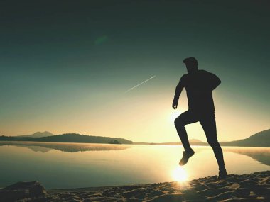 Gün doğumunda yansımayla plajda koşan bir çocuk. Açık gökyüzü ile Sabah Koyu Sahili.