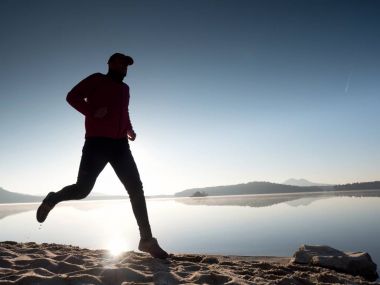 Güzel bir gün batımı fon karşı sahilde koşan adam. Kum dağ gölü