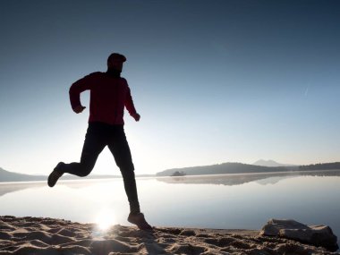Uzun kumsalda hızlı deniz kıyısında koşan adam uygun. Güçlü runner yaz sabah açık eğitim.