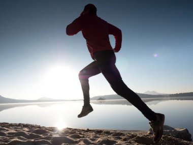 Güzel bir gün batımı fon karşı sahilde koşan adam. Kum dağ gölü