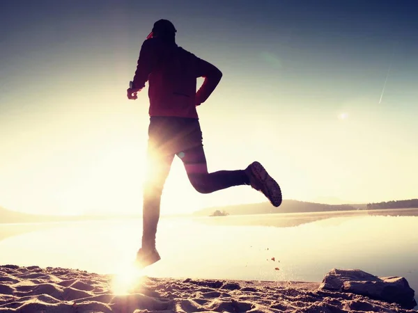 Hombre alto en forma corriendo rápido por el mar en la playa. Potente entrenamiento de corredor al aire libre en la mañana de verano . — Foto de Stock