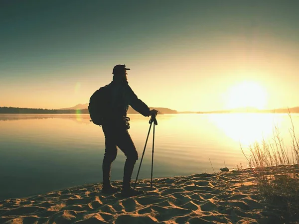모래 해변에 서 있는 배낭과 트레킹 폴란드와 남자 관광. 등산객을 즐길 — 스톡 사진