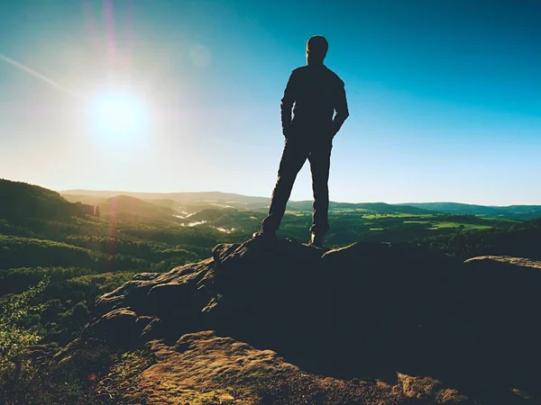 Mann steht auf dem Gipfel des Sandsteinfelsens und wacht über das Tal bis zur Sonne. schöner Moment — Stockfoto