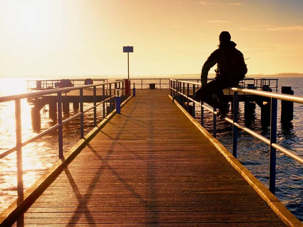 Einsamer Mann geht im Sonnenaufgang auf den Holzsteg — Stockfoto