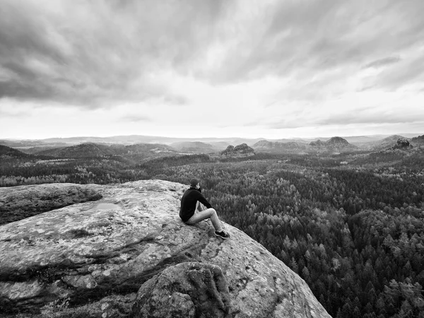Шукаю горизонт. Чоловік сидить на скелі над густими лісами або джунглями і насолоджується видом . — стокове фото