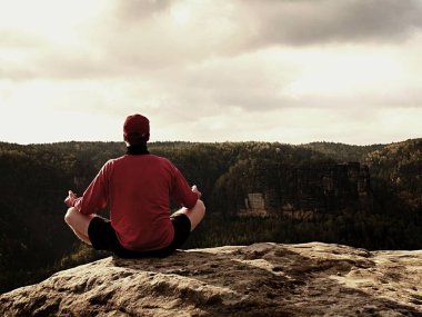 Yalnız adam kayalar tepe üzerinde Yoga poz puslu sabah içinde yapıyor. Orta yaşlı adam pratik Yoga