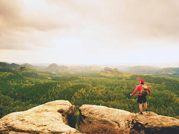 Turista en ropa deportiva negro rojo, mochila verde en el punto de vista reloj paisaje . — Foto de Stock