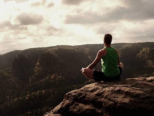 Hombre meditando en Lotus Pose en un acantilado rocoso. Deportista practicando Yoga en el borde de piedra —  Fotos de Stock