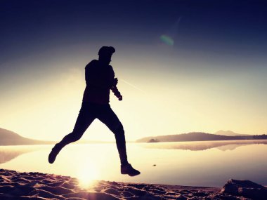 Gün batımında sahilde koşan bir adam. 