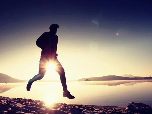 Muž běží na pláži při západu slunce — Stock fotografie