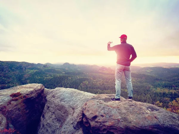 Amateur takes photos with phone on peak of rock. Dreamy landscape, Sun hang on horizon — Stock Photo, Image
