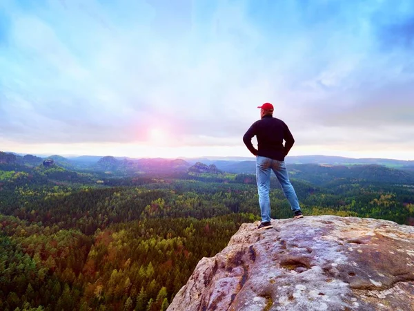 Wandelaar man blijft op een rotsachtige bergkam en genieten van uitzicht op lange vallei aan de horizon. Cold Sun verborgen in de wolken — Stockfoto