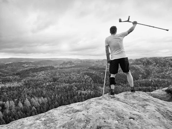 Mutlu bir adam tıp koltuk değneği diz küme ayracı özelliği sabit kafa, yaralı diz yukarıda tutarak uzun yürüyüşe çıkan kimse