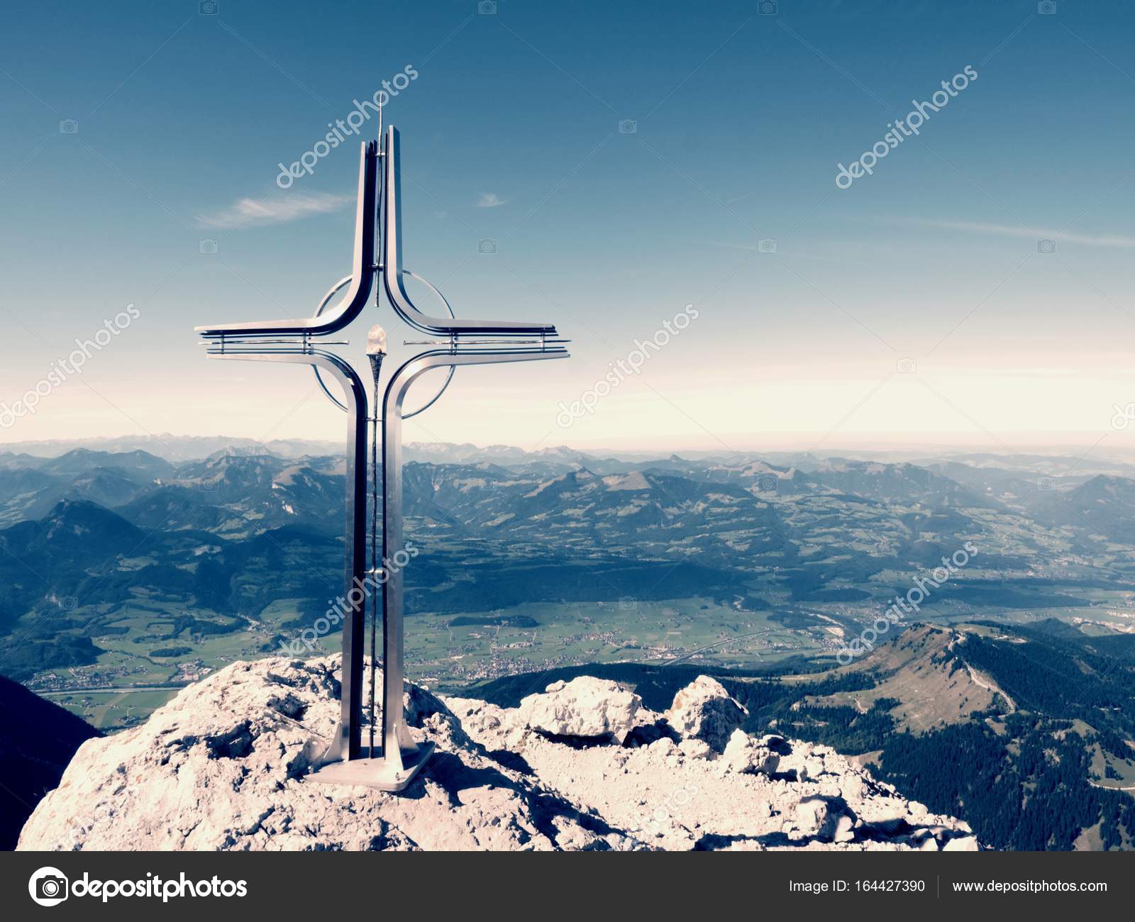 Praying cross raised at mountain summit in Alps. Sharp peak, daybreak