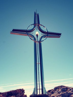 Dua eden çapraz Alpleri'nde dağın zirvesinde kaldırdı. Sivri tepe, şafak Güneş gökyüzünde. Çelik haç