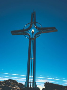 Yüksek kayalık dağ üzerinde çapraz Zirvesi dua. Çelik sanatsal haç Alp dağın zirvesinde