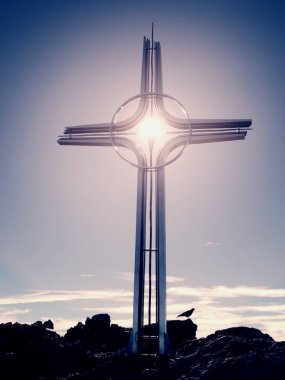 Yüksek kayalık dağ üzerinde çapraz Zirvesi dua. Çelik sanatsal haç Alp dağın zirvesinde