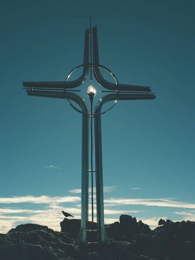 Yüksek kayalık dağ üzerinde çapraz Zirvesi dua. Çelik sanatsal haç Alp dağın zirvesinde