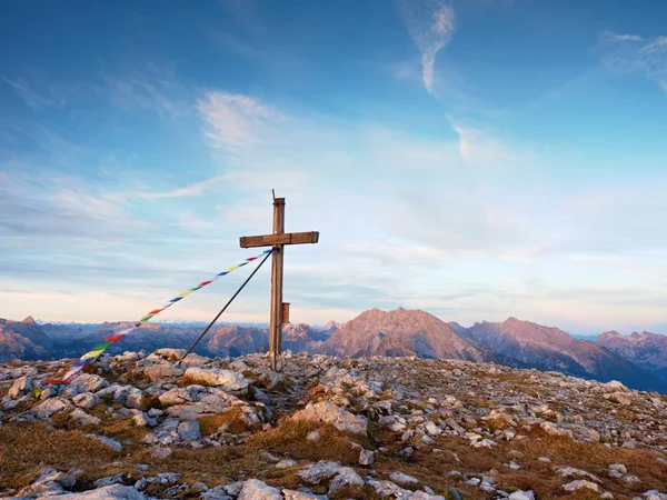 Biddende vlaggen wapperen in de wind over de top Kruis. Houten kruisbeeld bovenop Alpine berg — Stockfoto