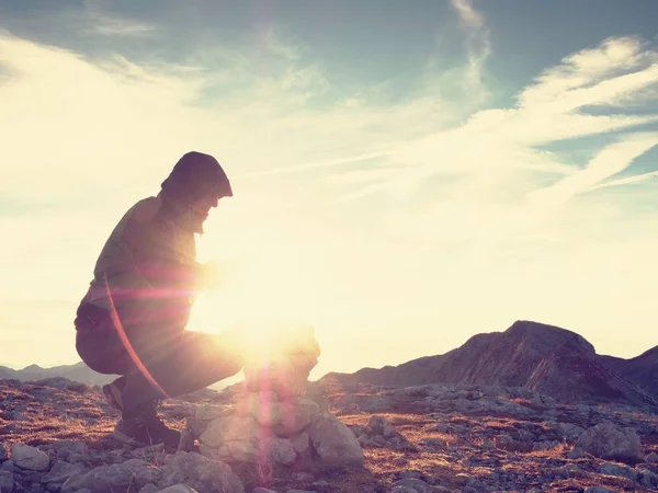 혼자 성인 남자는 피라미드에 돌을 여기 비축과 됩니다. 알프스 산 정상, 태양이 지평선에서 저녁. — 스톡 사진