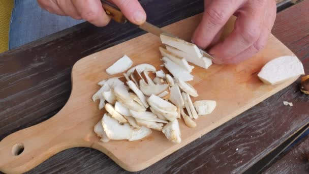 Güzel yabani mantar bıçakla Ahşap doğrama tahtası üzerinde küçük parçalar halinde kesilir. Adam ellerini çörek dilim ahşap masanın üstüne kesmek — Stok video