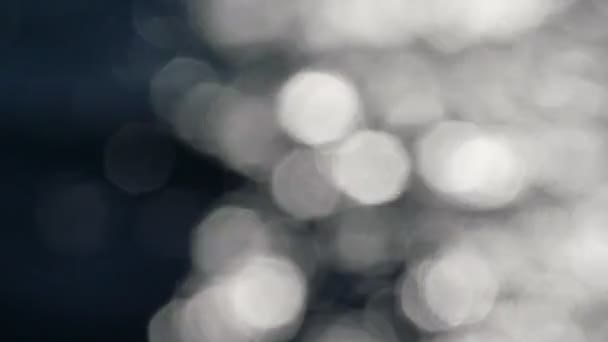 Mouvement lent de l'eau brillante et pétillante dans l'obscurité. Mouvement lent, fond flou abstrait au niveau de l'eau . 