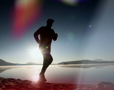 Kaçak ışık objektif. Sabah güneş karşı adam siluet egzersiz.