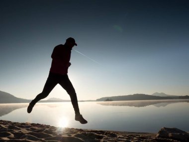 Güzel bir gün batımı fon karşı sahilde koşan adam. Kum dağ gölü