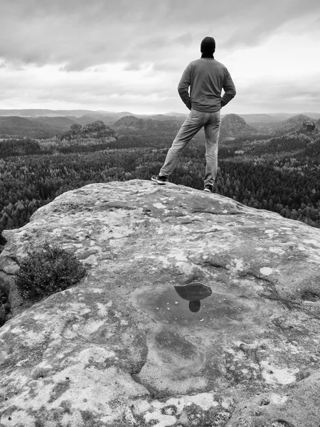 Турист остается на скалистом хребте и наслаждается видом на длинную долину до горизонта. Холодное солнце скрыто в облаках — стоковое фото