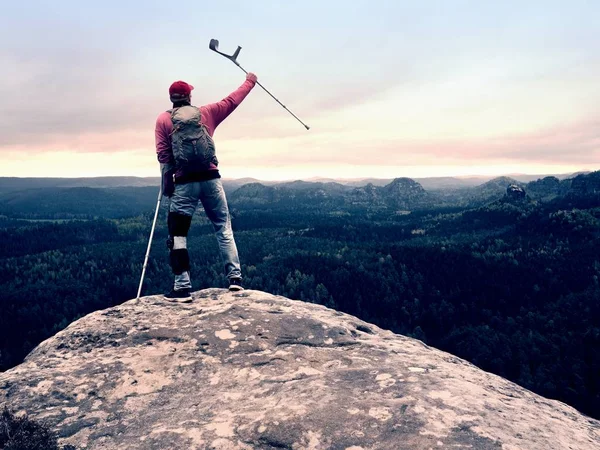Tepe zafer. Adam bacak diz kafesleri ve istikrar ve yürüme destek için koltuk değneği ile.