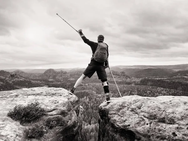 Τουρίστας με ιατρική δεκανίκι πάνω από το κεφάλι επιτευχθούν κορυφή του βουνού. Πεζοπόρος με σπασμένο πόδι — Φωτογραφία Αρχείου