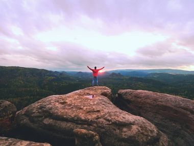 Adam hiker keskin cliff üzerinde. Zirveye kadar tırmandı hiker görünümü keyfini çıkarın. Sabah Vadisi üzerinde dikkat et