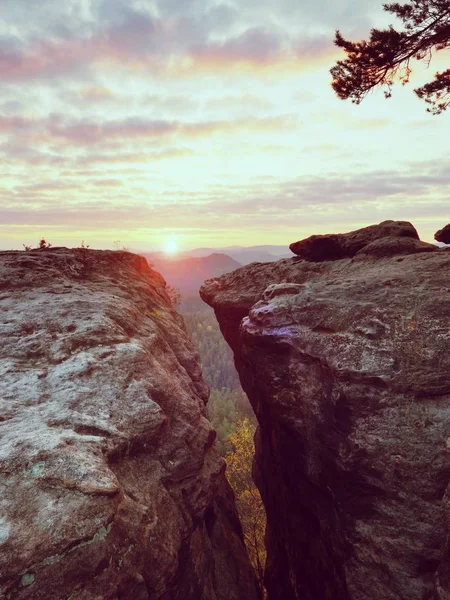 Spring morning nature. The cracked sandstone cliff above forest valley, daybreak Sun at horizon — Stock Photo, Image