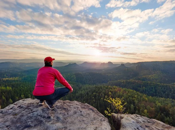 Un turista single siede su un impero roccioso. Punto di vista con vetta rocciosa esposta sopra valle . — Foto Stock