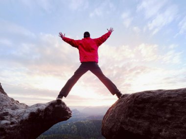 Mutlu bir adam havada rams ile zafer jesti. Kaya tepe üzerinde komik fiyatı