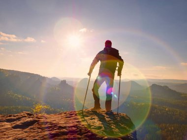 Turist izinde başının üstünde ön kol koltuk değneği ile. Uzun yürüyüşe çıkan kimse elde dağ tepe zarar