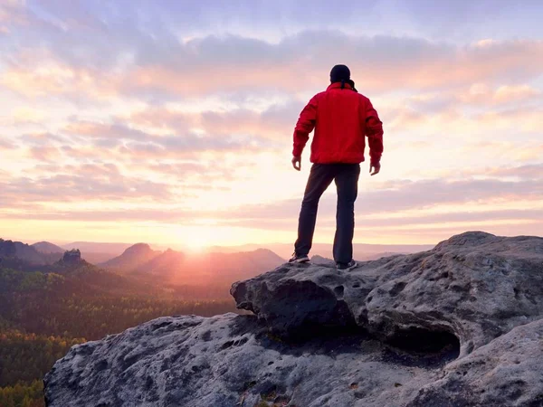 Keskin cliff üzerinde kırmızı ceketli erkek figürü. Dağlar erken sonbahar daybreak içinde — Stok fotoğraf