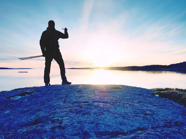 海で selfie を取って旅行男の背面のシルエット。バックパック立っている岩の上の観光客 — ストック写真