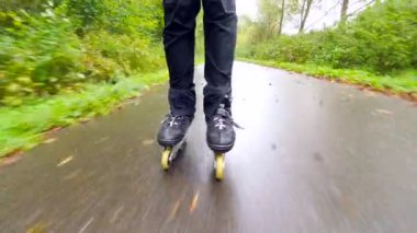 Sonbahar ormandaki ıslak kaygan asfalt üzerinde açık paten. Siyah pantolon çalışan adam bacaklar. Satır içi çizme sonbahar ccolorful yapraklarla kaplı yolda hızlı hareket.. 