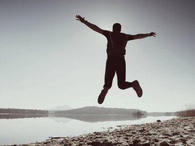 Kumsalda atlama deli adam. Kumsalda güneşin ufuk yukarıda sırasında uçan sporcu