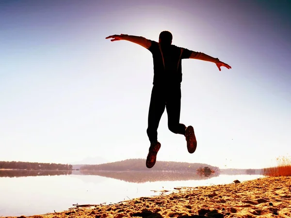 Kumsalda atlama deli adam. Kumsalda güneşin ufuk yukarıda sırasında uçan sporcu