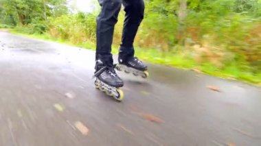 Sonbahar ormandaki ıslak kaygan asfalt üzerinde açık paten. Siyah pantolon çalışan adam bacaklar. Satır içi çizme sonbahar ccolorful yapraklarla kaplı yolda hızlı hareket.. 