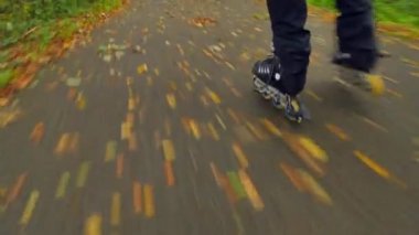 Sonbahar ormandaki ıslak kaygan asfalt üzerinde açık paten. Siyah pantolon çalışan adam bacaklar. Satır içi çizme sonbahar ccolorful yapraklarla kaplı yolda hızlı hareket.. 