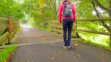 Açık paten. Sporcu pembe ve siyah spor giyim siyah paten ve siyah sırt çantası içinde. Hızlı bir şekilde yere blading Park, renkli ıslak asfalt yolda bırakır bir numara 
