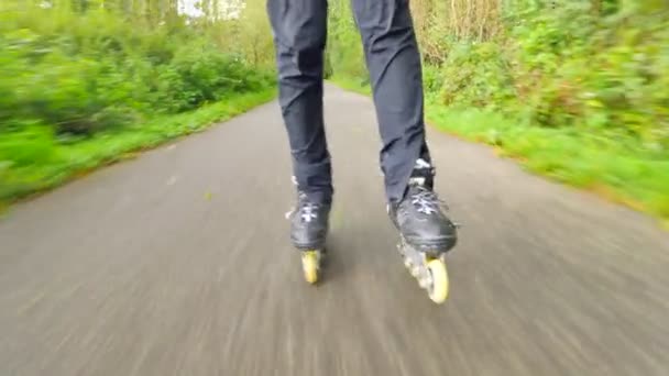 Patinage à roues alignées en plein air sur asphalte glissant humide dans la forêt automnale. Jambes d'homme en pantalon de course noir. Mouvement rapide des bottes en ligne sur la route couverte de feuilles colorées automnales .. — Video