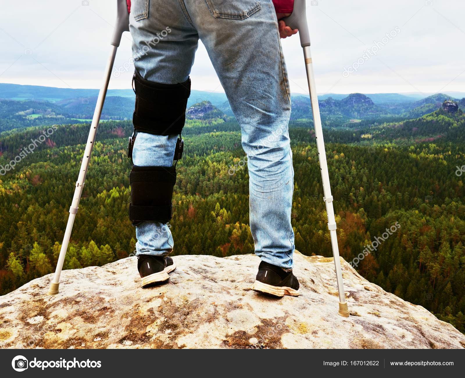 Man Walking With Crutches in nature. Man legs in jeans with adjustable