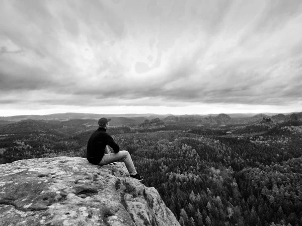 Blick zum Horizont. Mann sitzt auf Felsen über dichten Wäldern oder Dschungel und genießt Aussicht. — Stockfoto