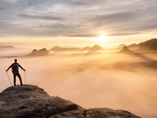 Männersilhouette mit Stangen in der Hand. Sonnenaufgang im Frühling und Reiseführer bleiben auf scharfen Klippen des Berges. — Stockfoto