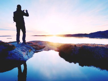 Cep telefonu dijital kamerada şaşırtıcı deniz manzara fotoğrafını çekmek turist adam.